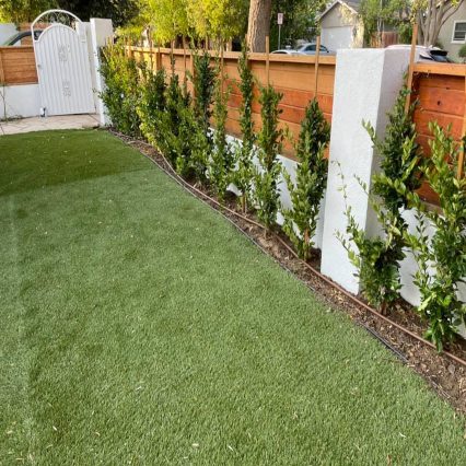 Fresh artificial turf with a raised planter bed installed by 2 Garzas Landscape